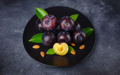 Sweet plums on dark background. Fresh blue plums with leaves. Food fruit Background. Summer postcard. Harvesting in garden, Harvest of plum