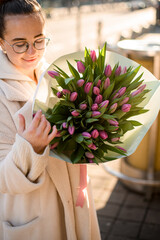 Young beautiful woman holding delicate bouquet of pink fresh tulips in hands