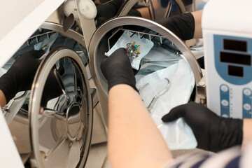 Hands in black gloves holding a medical instrument. Sterilizing box. Sterilization of instruments. Dentist tools. Sterilization procedure. Steam autoclave.