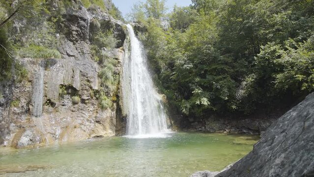 Waterfall between rocks and green trees