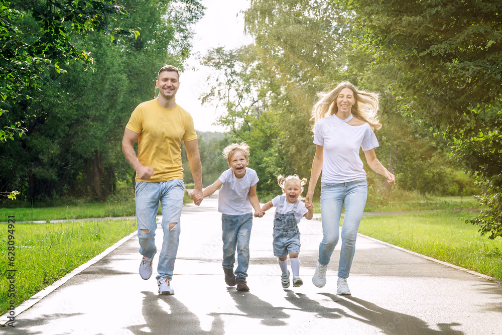 Wall mural happy family with two children joyfully run in the park on a sunny summer day. parents, son and daug