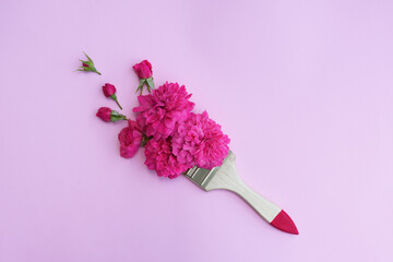 Flowers composition. Creative layout made of pink roses with buds and paint brush on pink background. Flat lay, top view.