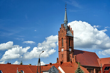 roofs made of red tiles and the bell tower of the historic gothic church in the village of Bledzew