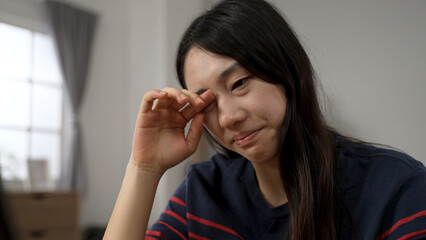 Fototapeta na wymiar closeup view of an Asian young woman suffering eye irritation is rubbing while learning from home at daytime during quarantine.