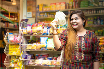 Indian woman showing money at grocery shop.