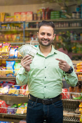 Indian man showing money at grocery shop.