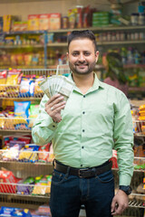 Indian man showing money at grocery shop.