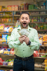Indian man holding money in hand and giving shocking expression at grocery shop