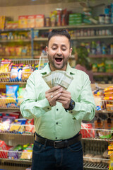 Indian man holding money in hand and giving shocking expression at grocery shop