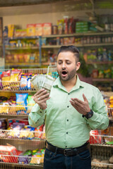 Indian man holding money in hand and giving shocking expression at grocery shop