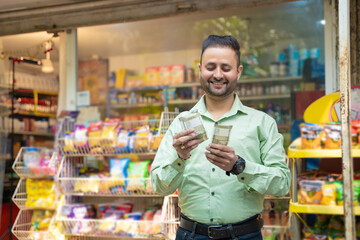 Indian man counting money at grocery shop.