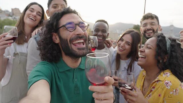 Multiracial friends drinking red wine outside at farm house vineyard countryside - Group of young people taking selfie picture outdoor - Life style concept with guys and girls enjoying summer vacation