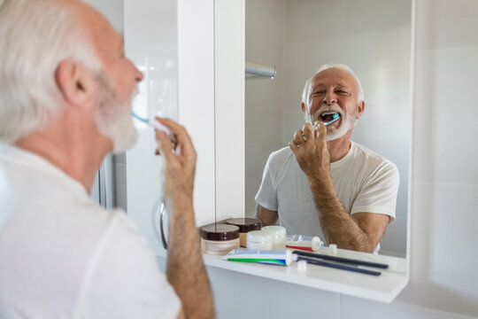 Shot of a senior man brushing his teeth in the bathroom.
