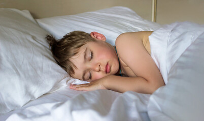 Defocused adorable little toddler boy sleeping in white bed. Child has a rest or a nap. Comfort concept. Soft focus