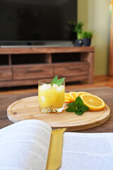 Glass of juice and ice with orange slices on a wooden cutting board
