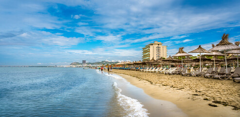 Golem, Durres, ALBANIA. Beach shoreline with sun umbrellas made from straw. A blue sky on the Adriatic Sea. - obrazy, fototapety, plakaty