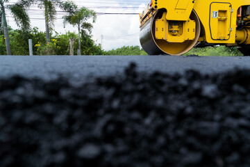 Yellow heavy vibrating roller on asphalt pavement Road construction, repairing rural road, sunny summer day. heavy equipment © wanakit