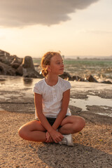 A cute cuacasian girl enjoys the moment against the backdrop of a restless sea and listens to the sound of the surf. 