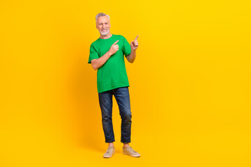Fototapeta premium Full body portrait of satisfied glad aged person direct fingers empty space offer news isolated on yellow color background