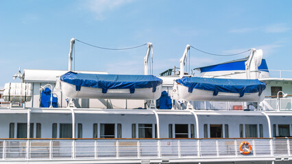 The upper deck of the ship with lifeboats. Windows on the ship. Summer navigation on the river. Rest on a pleasure liner. River and sea transport.