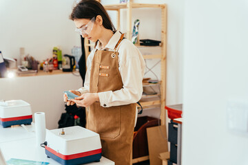 Side view of female artist feeling thoughtful working on new project in small studio or workshop.