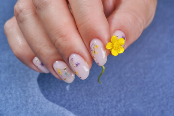 The nails are covered with gel polish and flowers. Nail design. Art painting of nails. Care for sensuality female hands. Shallow depth of field