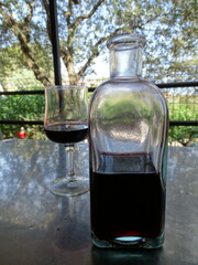 copa y jarra de vino tinto en mesa de afuera de un restaurante