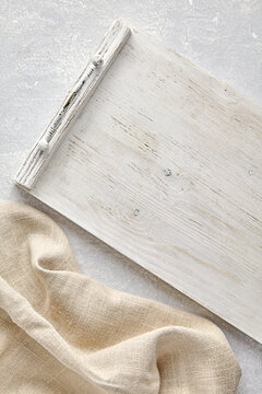 White wooden painted Provence serving tray and coarse linen beige kitchen towel on gray stone table Top view with copy space