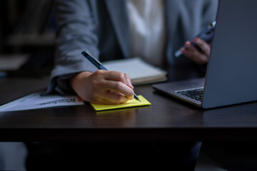Close-up shot of asian businesswoman using phone to find new ideas to prepare business plan.