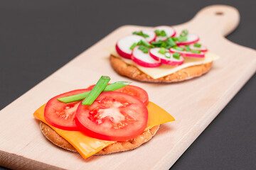 Different Cracker Sandwiches with Tomato, Cucumber, Radish and Cheese on Cutting Board. Easy Breakfast. Diet Food. Quick and Healthy Sandwiches. Crispbread with Tasty Filling. Healthy Dietary Snack