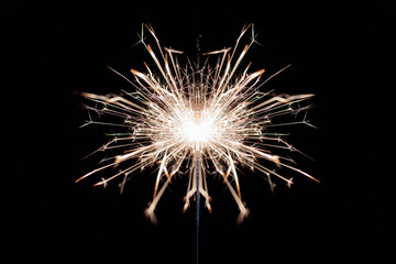 Burning sparkler on a dark background.