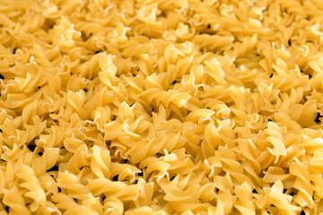 Uncooed Fusilli Pasta - Background. Texture of Bright Golden Dry Macaroni