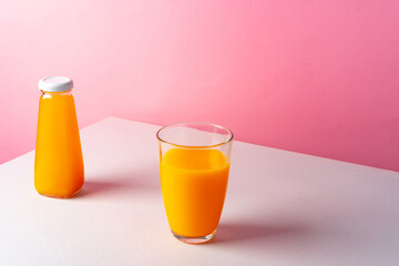 Orange juice on white table against pink background