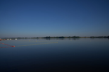 Plaża i kąpielisko, zbiornik wodny z możliwością kompania, lato nad wodą błękitne bezchmurne niebo na dole woda.