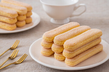 Lady finger biscuits, Italian dessert and sponge cookie on white plate and coffee cup