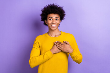 Portrait of positive friendly young man toothy smile arms touch heart thankful isolated on purple...