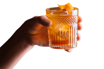 Bartender holds an orange cocktail with orange peel
