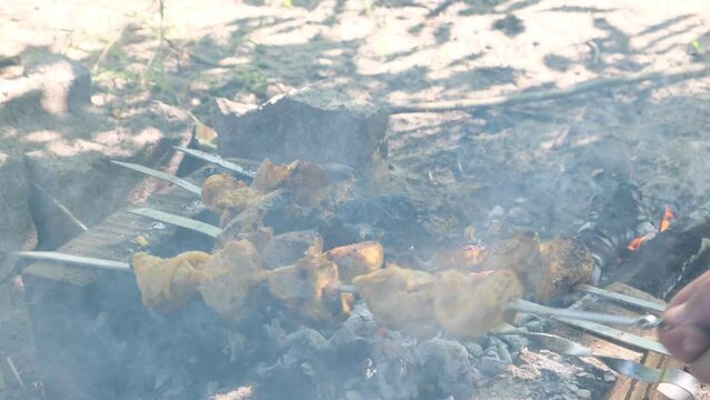 a man roasts meat on a fire. Close-up of hands and shish kebab. Cooking pork neck on the grill. Roasted carrots. Fatty food, festive food of the CIS countries. May 1, labor day. Not vegan food.	