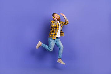 Full length photo of cheerful positive man wear stylish clothes have fun listen music wireless earbuds isolated purple color background