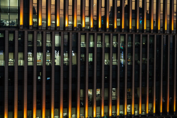 Offices seen through illuminated windows after sunset, modern city night view with reflections in architecture