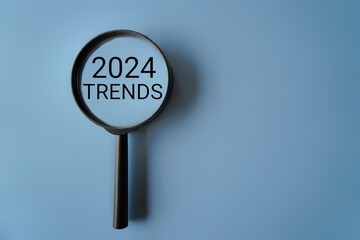 Magnifying glass and text 2024 TRENDS on blue background with copy space