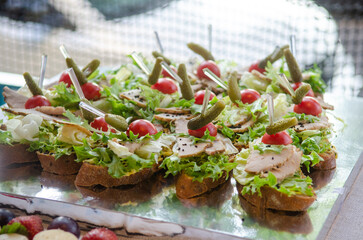Catering in the evening, small chicken and pickled cucumber sandwiches on plates in the sunlight