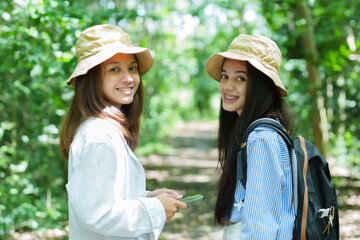 Best friend, teenage girl, two Asian girl standing smiling in the community forest On my father's day, I walk along the nature trail happily while watching various birds.