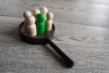 Wooden dolls on top of magnifying glass. Human resources, target market and audience, focus group concept