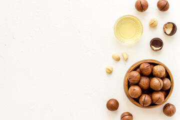 Bowl of of macadamia nuts oil with raw nuts. Natural oil for cosmetic or cooking