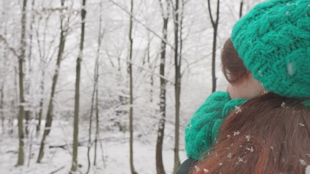 Winter holidays are in full swing. A woman rests in nature, enjoying the winter beauty and fresh air. Winter idyll: a young girl enjoys a walk outdoors in a picturesque snow-covered forest.