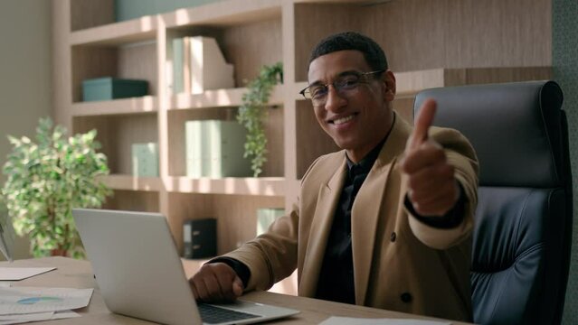 African American man happy glad businessman smiling entrepreneur office manager working laptop looking at camera smile show thumb up finger gesture recommend good business idea opportunity achievement