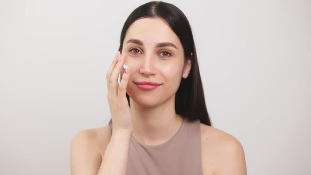 Slow motion portrait young woman uses creams of her face. Concept for fresh moisturized skin beautiful closeup cosmetic face happy healthy model. Young blonde hair woman take care of her skin.