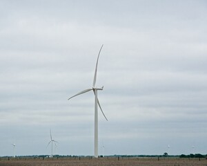 Wind farm in agricultural fields of Kansas open plains against cloudy sky
