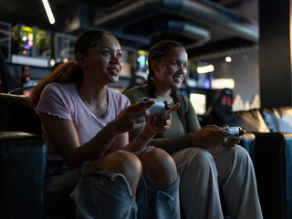 Plakat Female friends playing video games in gaming club